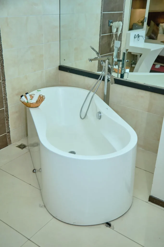 Freestanding oval bathtub beside a tiled wall