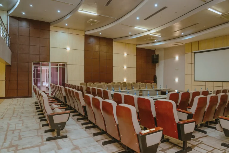 Rows of conference chairs leading to a projection screen