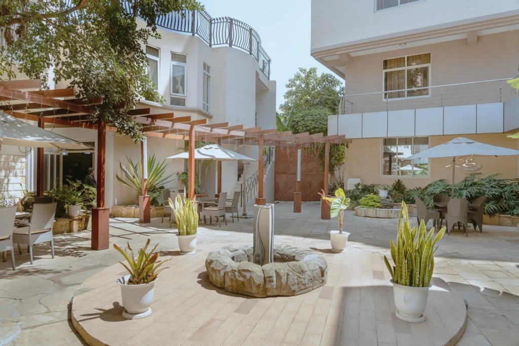 Courtyard with a stone fountain, timber pergola, potted plants and dining tables