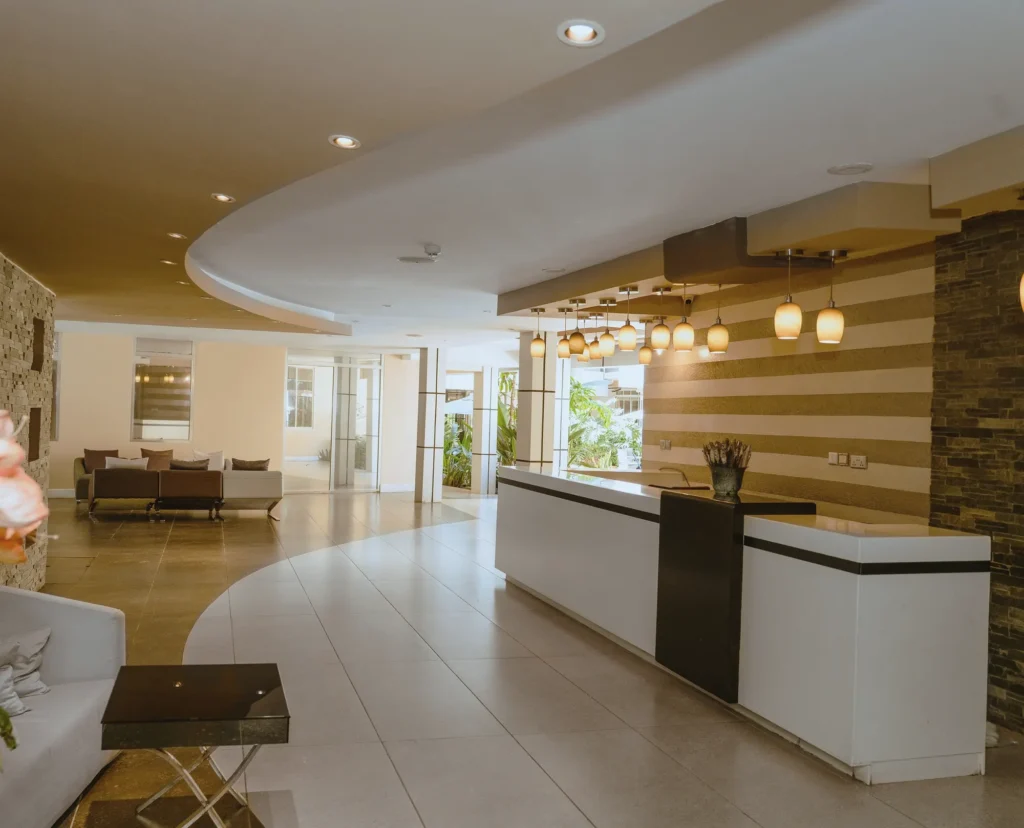 Reception desk under a curved ceiling with pendant lights and a stone feature wall