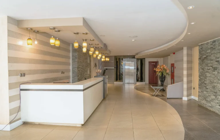 Lobby with a white reception counter, striped stone wall and warm pendant lights
