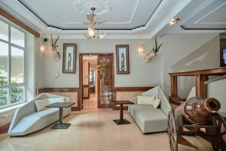 Sitting area with white sofas, framed carvings, antelope heads and a timber cannon
