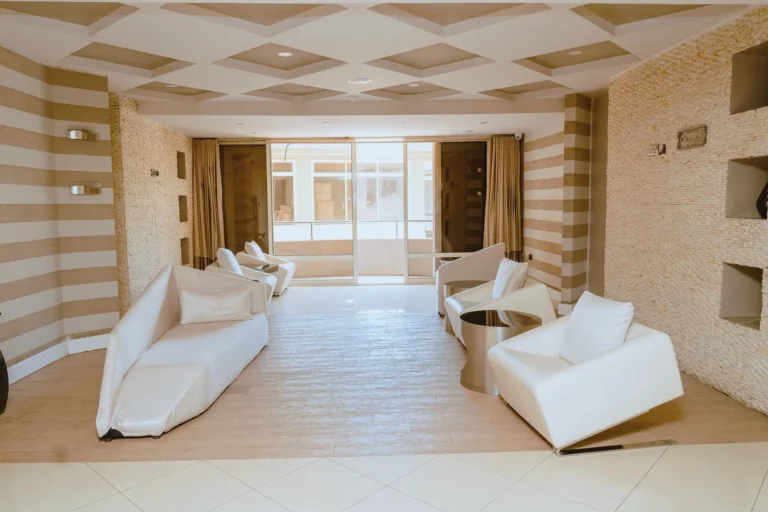 Sitting room with sculptural white chairs, striped stone walls and a coffered ceiling