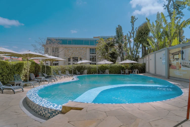 Kidney-shaped pool with a mosaic edge, sun loungers, umbrellas and banana palms