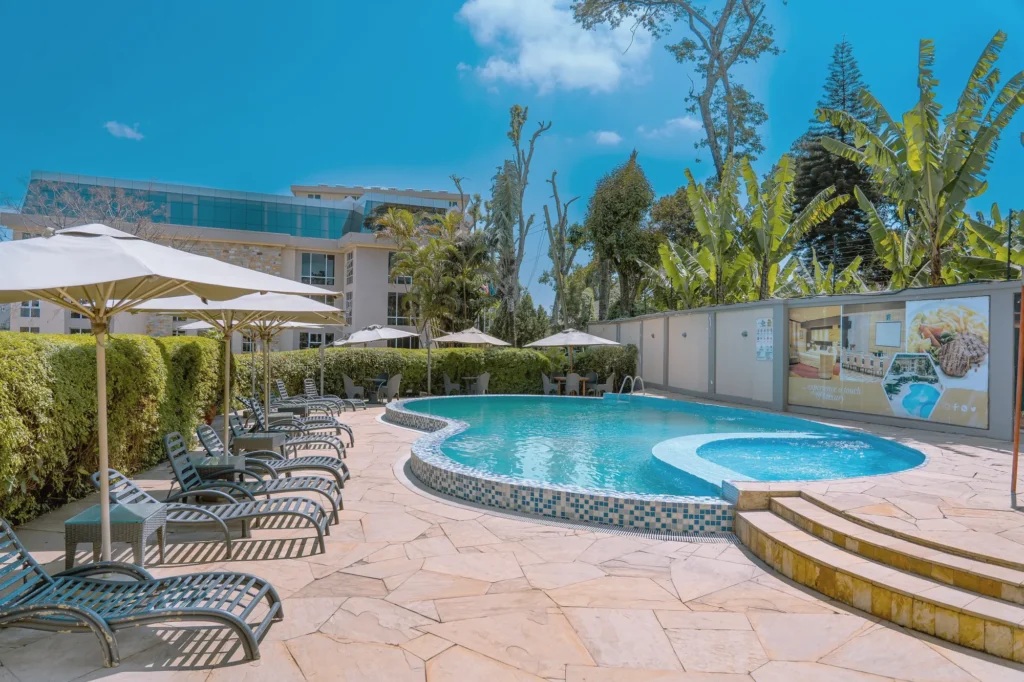 Pool deck with loungers and umbrellas beside a curved pool and a shallow children's section