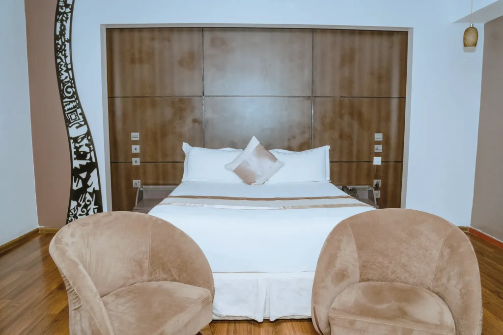 Queen Room with a panelled headboard wall, a carved black screen and two tub chairs