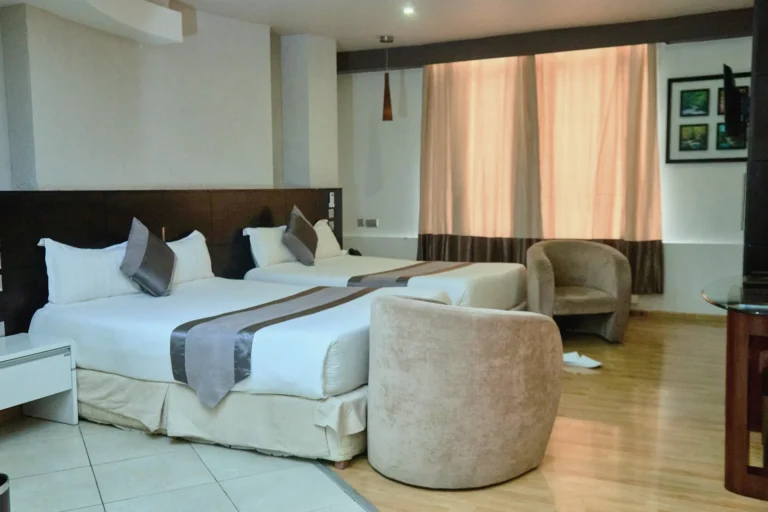Family room with two queen beds, grey runners and tub chairs